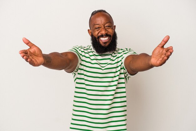 Afro-Amerikaanse man met baard geïsoleerd op roze muur voelt zich zelfverzekerd en geeft een knuffel