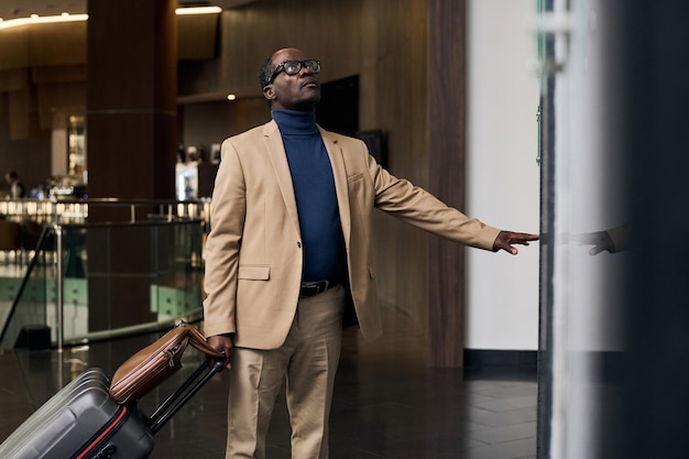 Afro-Amerikaanse man met bagage die op de knop drukt en op de lift wacht