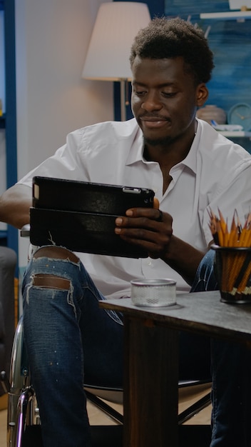 Afro-amerikaanse man met een handicap met behulp van digitale tablet