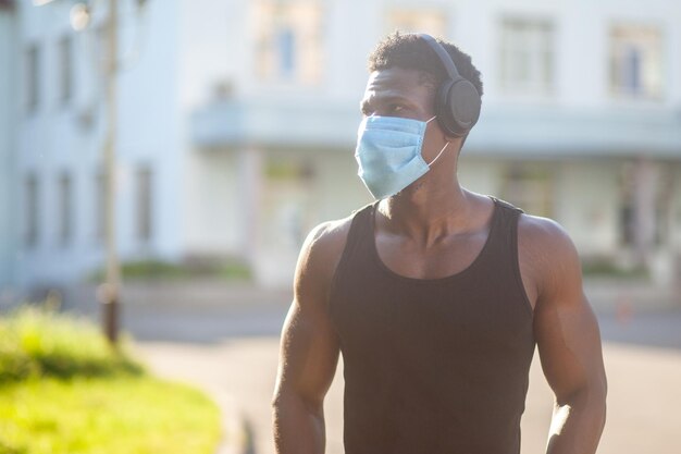 Afro-Amerikaanse man met een medisch masker staat buiten tegen de achtergrond van de stad