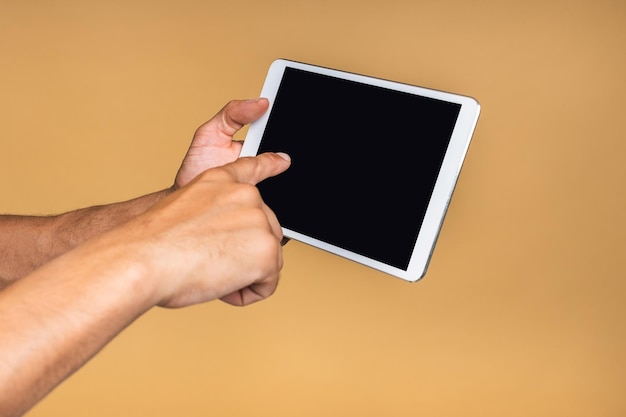 Afro-Amerikaanse man met een tablet geïsoleerd op beige achtergrond Copyspace Close-up concept Hand met tabletcomputer