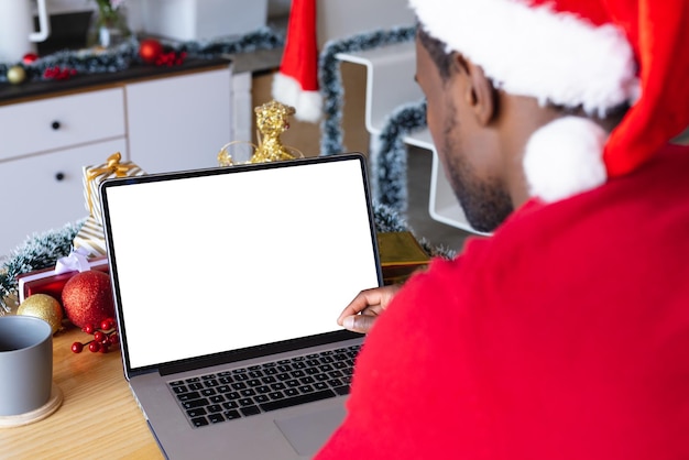 Afro-Amerikaanse man met kerstmuts, met behulp van laptop met copyspace