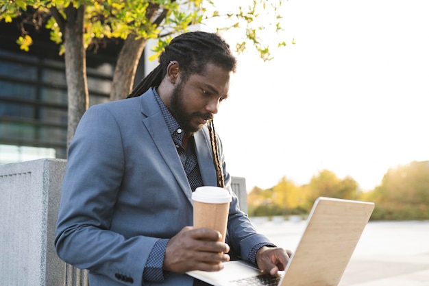 Afro-Amerikaanse man met laptop en koffie op straat