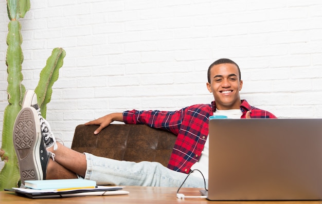 Afro-Amerikaanse man met laptop in de woonkamer kijken naar een film in de laptop