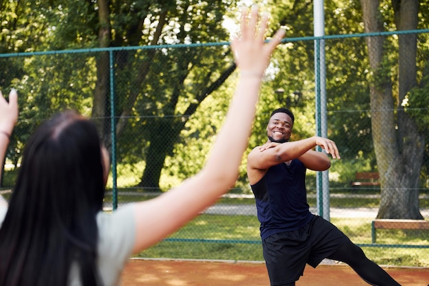Afro-Amerikaanse man met meisje speelt basketbal buiten op het veld