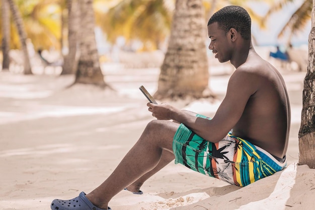 Afro-Amerikaanse man met smartphone onder palmboom