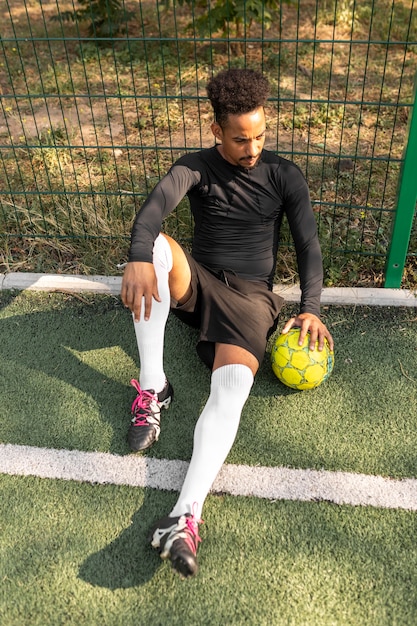 Afro-Amerikaanse man poseren met een voetbal buiten