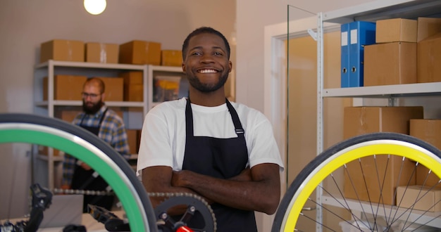 Afro-amerikaanse man reparatie fiets in garage werkplaats glimlachend op camera