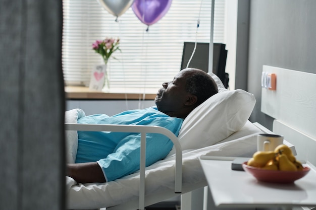 Afro-Amerikaanse man slaapt op bed terwijl hij wordt behandeld in de ziekenhuisafdeling