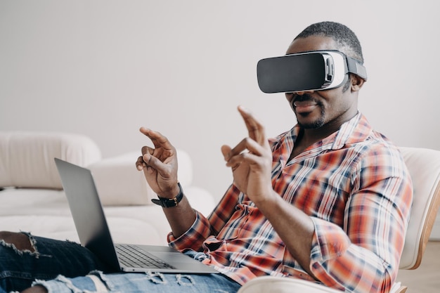 Afro-Amerikaanse man software-ontwikkelaar in virtual reality-bril die in cyberspace op laptop werkt