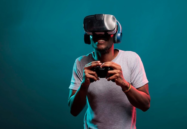 Afro-Amerikaanse man speelt videogame met controller en vr-headset, geniet van online spelen met futuristische 3D-simulatie in studio. Gamer met virtual reality-bril met joystick.