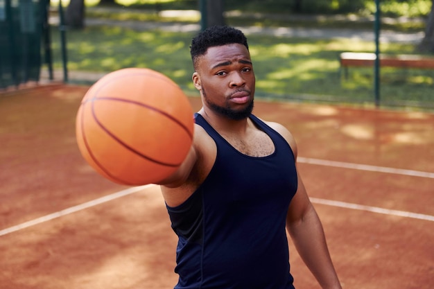 Afro-Amerikaanse man staat met bal op het veld buitenshuis