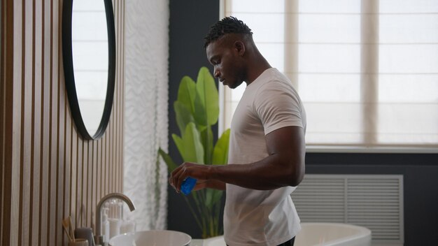 Afro-Amerikaanse man tanden schoonmaken spoelen met tandheelkundig product mondhygiëne in de badkamer spoelen