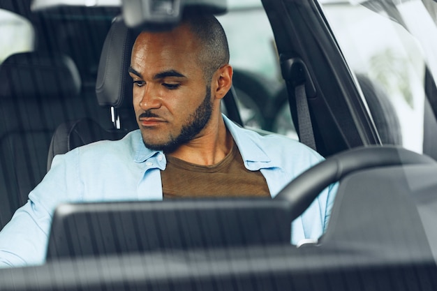 Afro-Amerikaanse mannelijke chauffeur zit in een auto