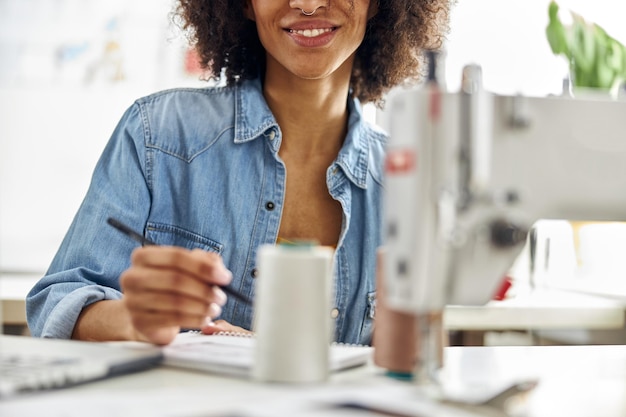 Afro-amerikaanse modeontwerper trekt kledingmodel op de werkplek in lichte studioclose-up