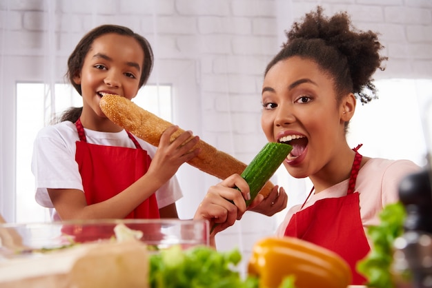 Afro-Amerikaanse moeder en dochter in schorten eten