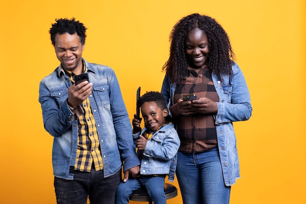 Afro-Amerikaanse ouders controleren hun smartphones naast het kind op de camera.