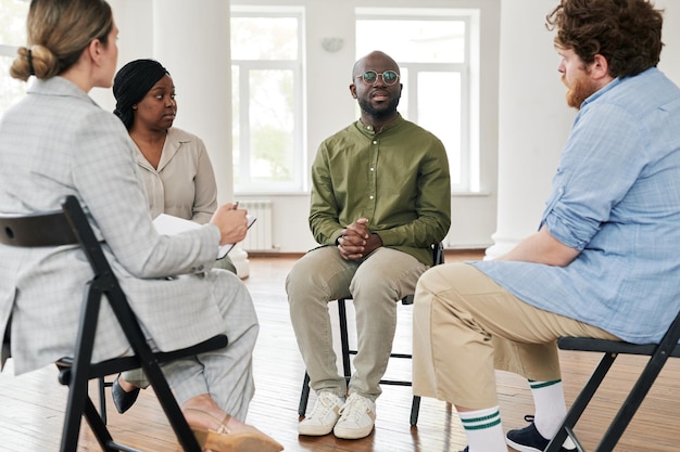 Afro-Amerikaanse patiënt die zijn probleem beschrijft aan psycholoog en andere mensen