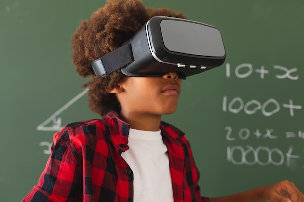 Afro-Amerikaanse schooljongen voor schoolbord in de klas met behulp van vr-headset