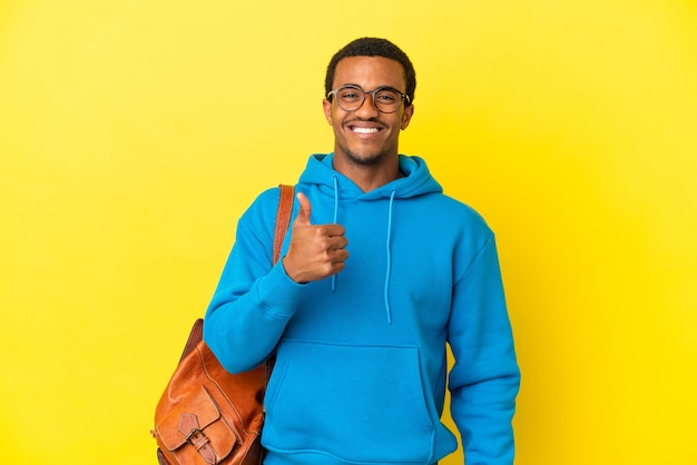 Afro-Amerikaanse student man over geïsoleerde gele achtergrond met een duim omhoog gebaar