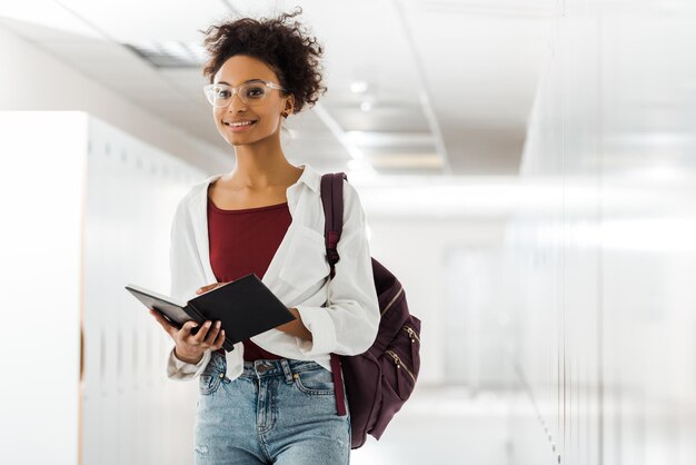 Afro-Amerikaanse student met notitieboekje in gang op de universiteit