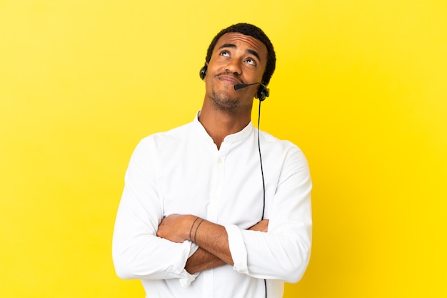 Afro-Amerikaanse telemarketeer man aan het werk met een headset over geïsoleerde gele achtergrond terwijl hij glimlacht