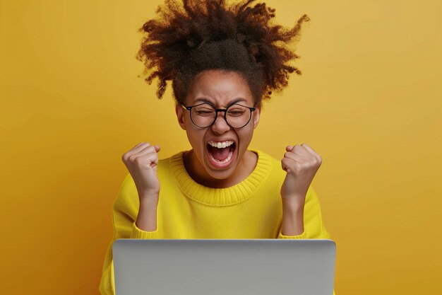 Afro-Amerikaanse tienervrouw opgewonden en feestelijk met laptop schreeuwend en vuist in handen winnaar van de wedstrijd