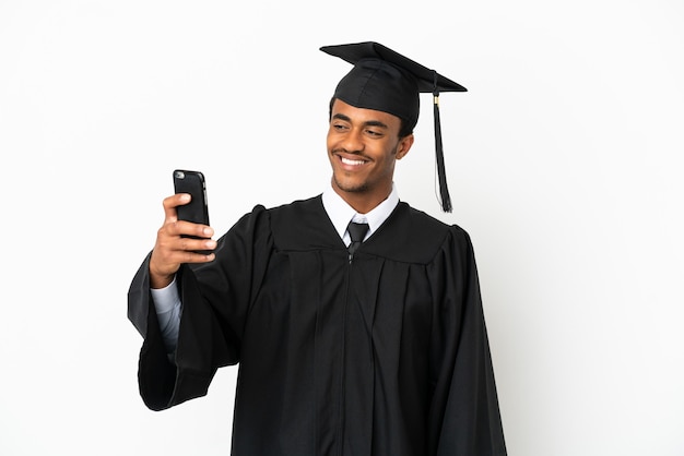 Afro-Amerikaanse universitair afgestudeerde man over geïsoleerde witte achtergrond die een selfie maakt