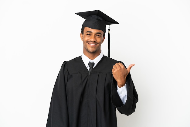 Afro-Amerikaanse universitair afgestudeerde man over geïsoleerde witte achtergrond wijzend naar de zijkant om een product te presenteren