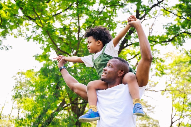 Afro-Amerikaanse vader geeft zoon ritje terug in het park Familieweekend