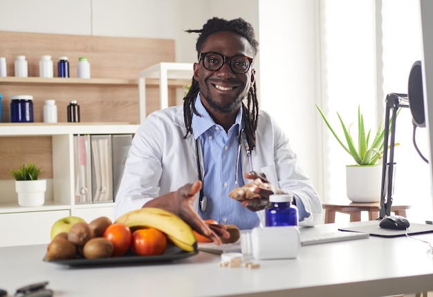 Afro-Amerikaanse voedingsdeskundige die naar de camera kijkt en gezond fruit laat zien in het consult