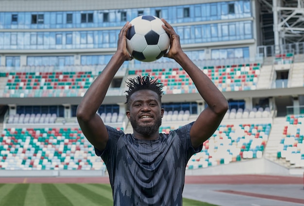Afro-amerikaanse voetballer die de bal in zijn handen houdt in het stadion