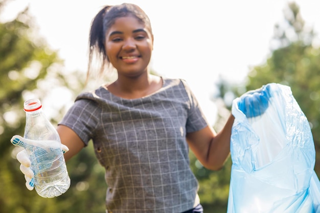 Afro-Amerikaanse vrijwilligers verzamelen plastic afval op een zonnige dag in het zomerpark