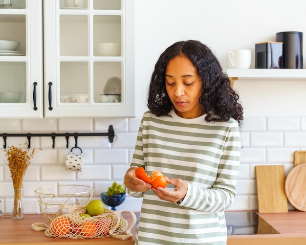 Foto afro-amerikaanse vrouw controleert sinaasappel citrus voor bederf in de keuken na het winkelen