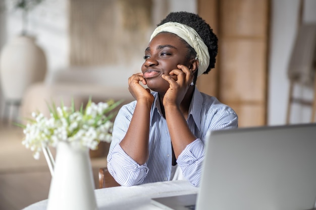 Afro-Amerikaanse vrouw die aan tafel zit en op een laptop werkt