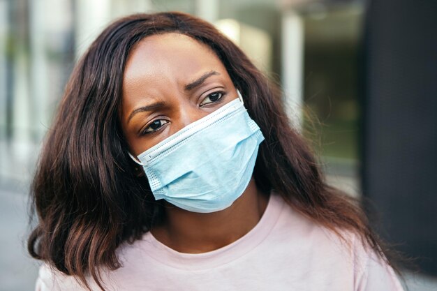 Afro-Amerikaanse vrouw die buiten staat, draagt een masker