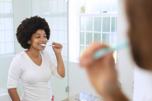 Foto afro-amerikaanse vrouw die in de badkamer staat en tanden poetst