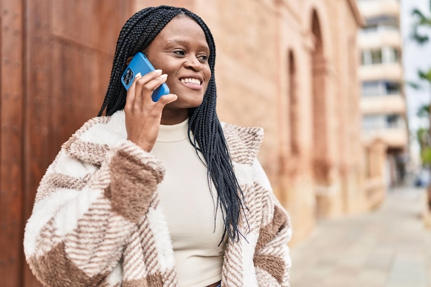 Afro-Amerikaanse vrouw die lacht zelfverzekerd praten op de smartphone op straat