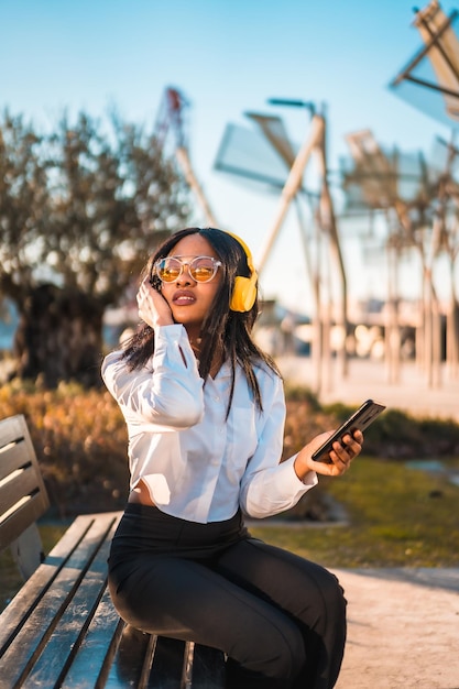 Afro-Amerikaanse vrouw die naar muziek luistert met een koptelefoon bij zonsondergang in een park