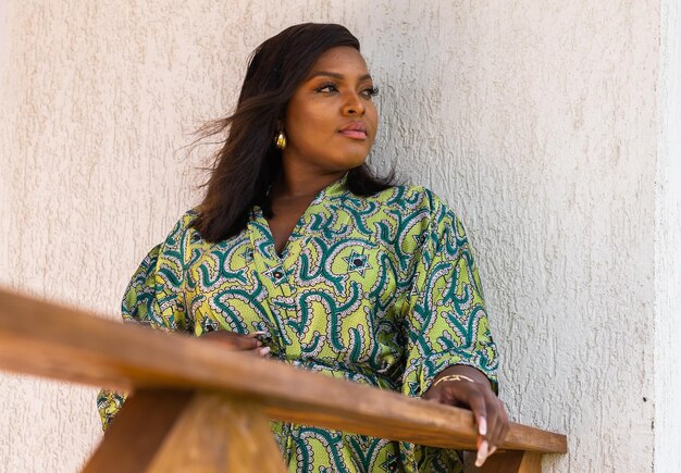 Afro-Amerikaanse vrouw die ontspant en geniet van de zon terwijl ze op het terras of balkon staat bij zonlicht