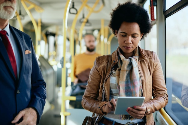 Afro-Amerikaanse vrouw die touchpad gebruikt tijdens woon-werkverkeer met het openbaar vervoer