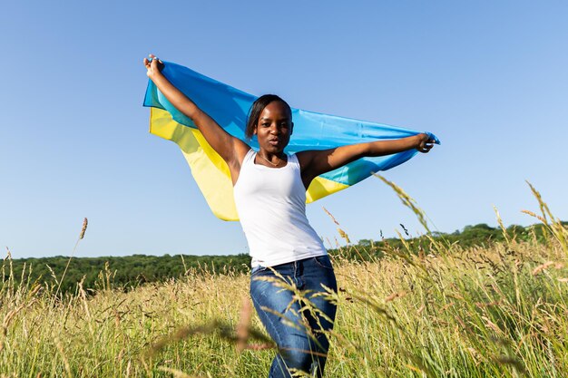 Afro-Amerikaanse vrouw gewikkeld in Oekraïens geel blauw vlag nationaal symbool van Oekraïne