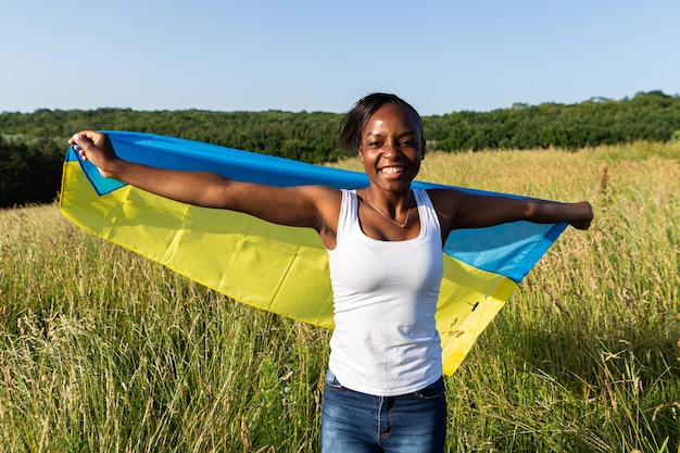 Afro-Amerikaanse vrouw gewikkeld in Oekraïens geel blauw vlag nationaal symbool van Oekraïne