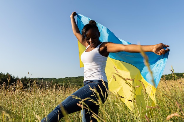 Afro-Amerikaanse vrouw gewikkeld in Oekraïens geel blauw vlag nationaal symbool van Oekraïne