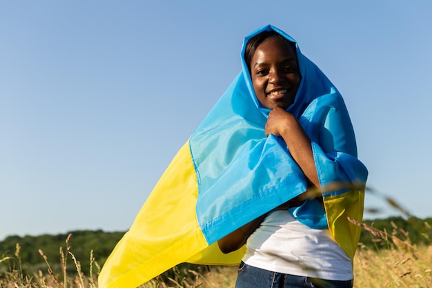 Afro-Amerikaanse vrouw gewikkeld in Oekraïens geel blauw vlag nationaal symbool van Oekraïne