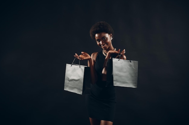 Afro-Amerikaanse vrouw houdt zwarte boodschappentassen Verkoop en kortingen op de markt en Black Friday-concept