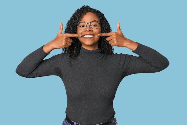 Afro-Amerikaanse vrouw in de studio glimlacht en wijst met haar vingers naar haar mond.