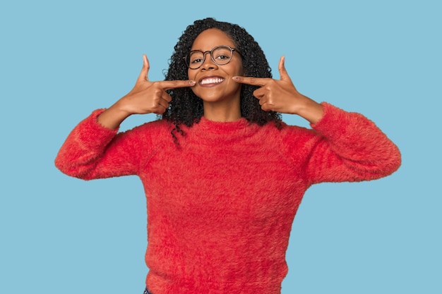 Afro-Amerikaanse vrouw in de studio glimlacht en wijst met haar vingers naar haar mond.