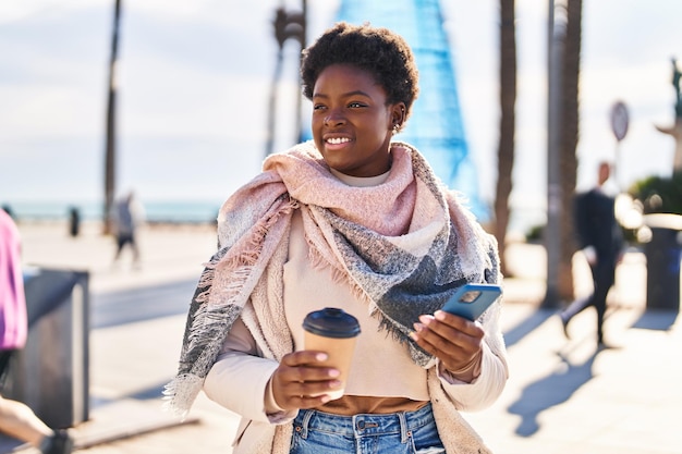 Afro-Amerikaanse vrouw met behulp van smartphone koffie drinken op straat