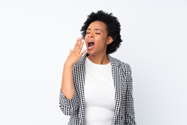 Afro-Amerikaanse vrouw met blazer op geïsoleerde witte geeuwen en kegel wijd open mond met hand